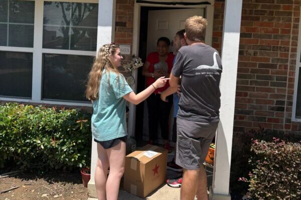 Clubhouse volunteers delivering a package to a community member at their front door during a community service project
