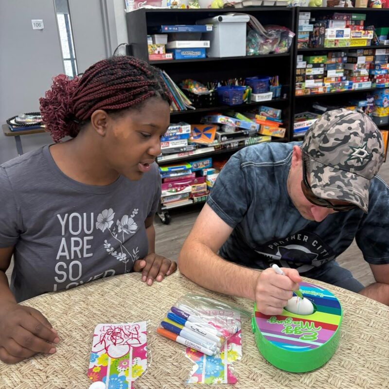 Two Clubbers using markers to decorate an egg during a creative arts activity