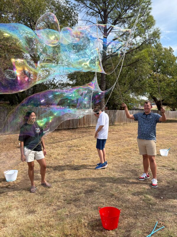 Clubbers and staff play with giant soap bubbles outdoors