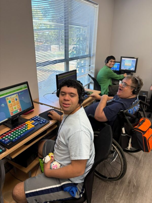 Clubbers wearing headphones work at computers during a functional literacy session