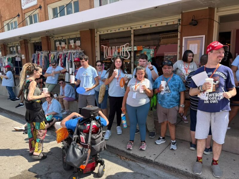 Clubbers and staff gather on a downtown sidewalk during a community outing